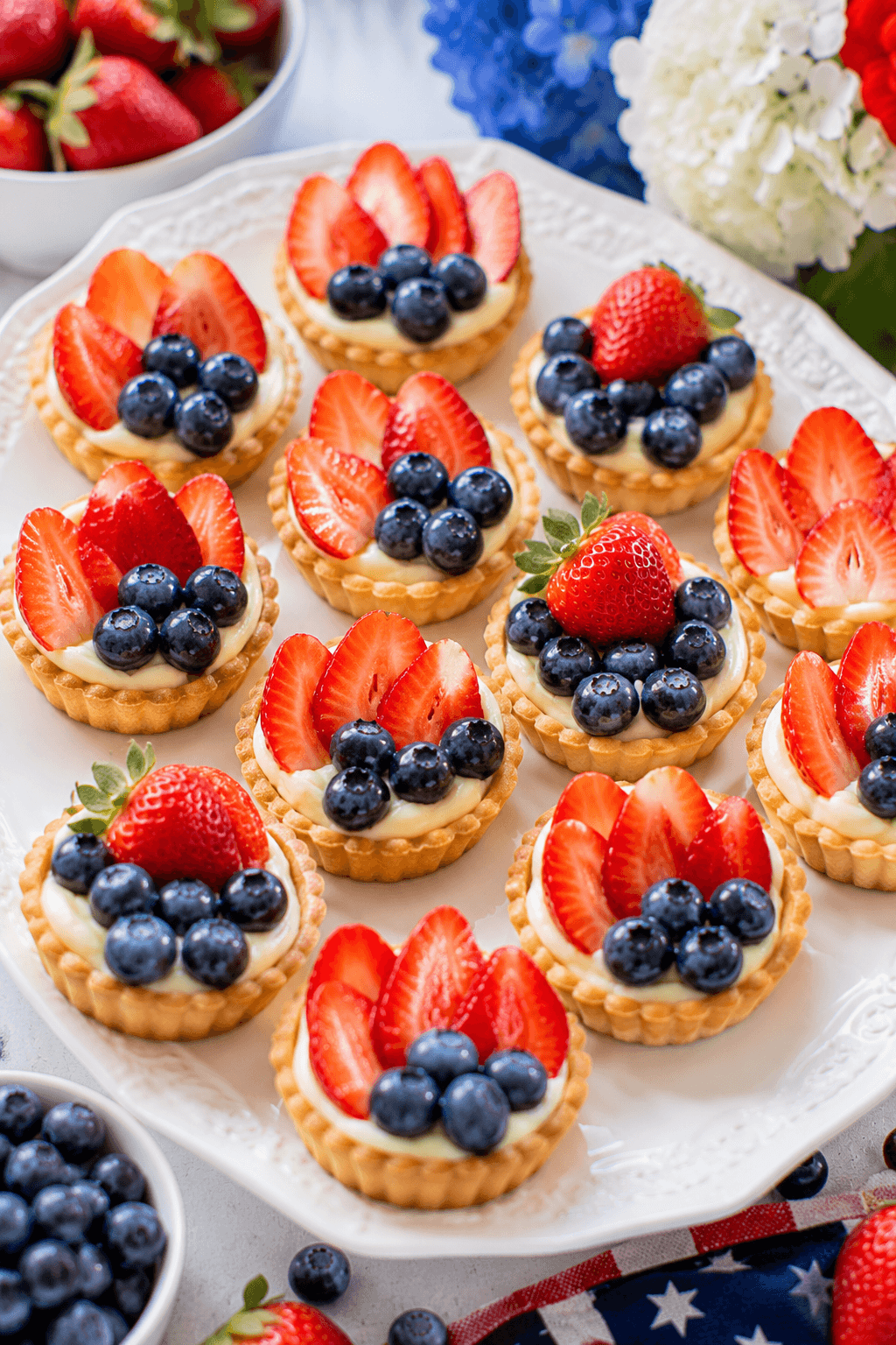 Mini fruit tarts topped with strawberries, blueberries, and cream